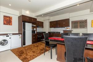 Una cocina con mesa y sillas y un refrigerador. en Naiharn beach sands Apartment, en Nai Harn Beach