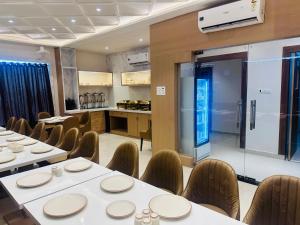 a restaurant with white tables and chairs and a kitchen at hotel deep palace in Varanasi