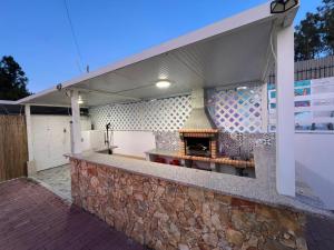 an outdoor kitchen with a stone counter with a fireplace at Sunset Pool Villa In Lisbon in Fernao Ferro