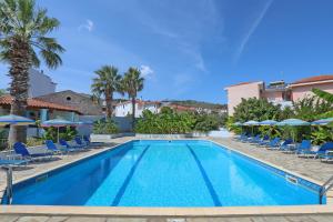 a large swimming pool with chairs and umbrellas at Dolphin Hotel in Skopelos Town +74 photos