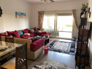 a living room with a red couch and a table at Amwaj ground apartment in El Alamein