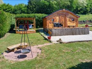 a small log cabin with a playground in the yard at Les cabanes féeriques d'Amoncourt in Amoncourt