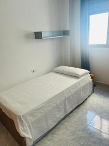 a bed in a room with white walls and a window at Apartamento completo in Burriana +11 photos