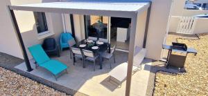 una vista dall'alto di un patio con tavolo e sedie di "LE BONHEUR EST DANS LE VEILLON" Maison neuve 3 chambres de 2025, 7 personnes, avec jacuzzi 6 personnes et climatisation réversible a Talmont