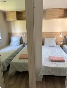 two beds in a small room with a mirror at Bungalow 410, 8 pers Camping 4 étoiles Siblu Le Lac des Rêves in Lattes +32 photos