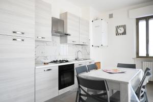 a kitchen with white cabinets and a table with chairs at PP07 - Porto Potenza, trilocale vista mare con aria condizionata in Porto Potenza Picena +22 photos