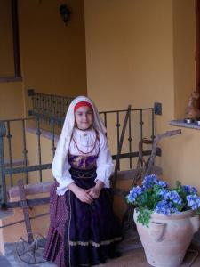 a young girl is sitting on a bench next to flowers at B&B San Leonardo in Muravera