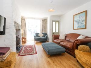 a living room with a brown leather couch and chairs at Llys Emrys in Caernarfon