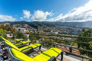 eine Reihe gelber Stühle auf einem Balkon mit Aussicht in der Unterkunft Casa Barcelos View in Funchal