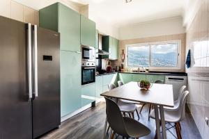 eine Küche mit grünen Schränken sowie einem Tisch und Stühlen in der Unterkunft Casa Barcelos View in Funchal