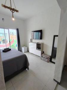 ein Schlafzimmer mit einem Bett, einem Spiegel und einem Fernseher in der Unterkunft KaBeat House Icaraizinho in Amontada