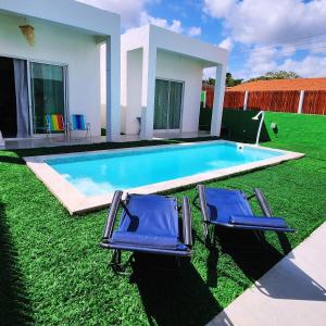 zwei blaue Stühle auf dem Rasen in der Nähe eines Pools in der Unterkunft KaBeat House Icaraizinho in Amontada