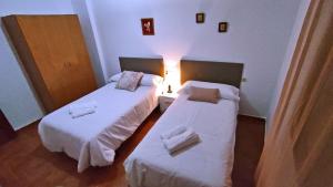 two beds in a small room with white sheets at Casa de Simona in Villar de Plasencia