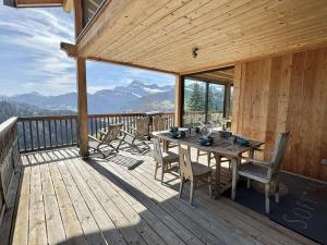 a wooden deck with a table and chairs on it at Chalet 8 pièces avec spa, sauna, 15 pers, à 800m des pistes, Notre-Dame-de-Bellecombe - FR-1-595-1 in Notre-Dame-de-Bellecombe