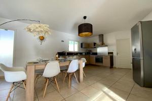 a kitchen with a wooden table and white chairs at Le Clos St Roch- Family home in Montpellier! in Montpellier