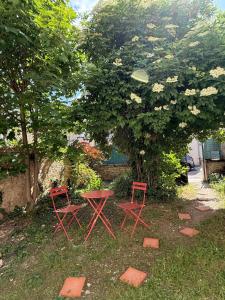 two red chairs and a table under a tree at Mini loft Spa - Cosy in Dijon