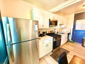 a kitchen with a stainless steel refrigerator and white cabinets at Midway Hideaway -Cozy 1BR- parking in Chicago