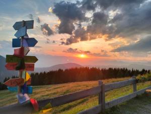a group of signs on a fence with a sunset at Malga Pontara in Bedollo