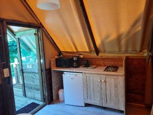 a small kitchen in a tent with a white refrigerator at Camping des Drouilhèdes in Peyremale