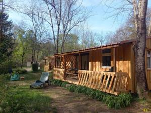 a wooden cabin with a bench and a tree at Camping des Drouilhèdes in Peyremale