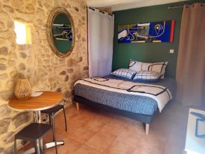 a bedroom with a bed and a table and a mirror at un pied dans la forêt in La Capelle-et-Masmolène
