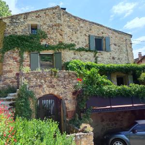 a stone house with a gate in front of it at un pied dans la forêt in La Capelle-et-Masmolène