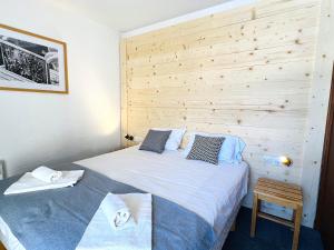 een slaapkamer met 2 bedden en een houten muur bij Hôtel Club Le 1850 Risoul in Risoul