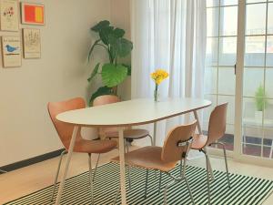 大邱Soo Stay的餐桌、椅子和一瓶鲜花
