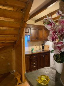 a kitchen with wooden cabinets and a vase of flowers at Domek Nad Rozlewiskiem z kominkiem in Baligród