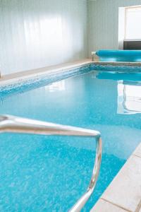 a swimming pool with blue water in a building at Vale Farm Cottages in Brecon