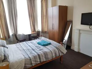 a bedroom with a bed and a tv and a fireplace at Abbey Lodge Guest House in Bournemouth