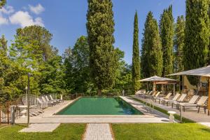 a swimming pool with lounge chairs and an umbrella at Tenuta Villa Febea in Chiusi