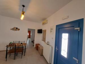 a room with a blue door and a table and a kitchen at Sunshine House in Serifos Chora
