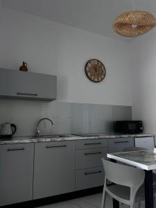 a kitchen with white cabinets and a clock on the wall at Apartamenty Róża Wiatrów in Solec-Zdrój