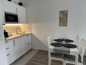 a kitchen with a table and chairs and a kitchen with white cabinets at Goldvilla Apartman in Zalakaros