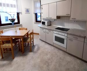 a kitchen with white cabinets and a table and a table and chairs at Großzügige, komfortable Wohnung in Burgstaedt