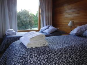 two beds with towels stacked on them in a bedroom at Las Cuatro Estaciones in San Martín de los Andes