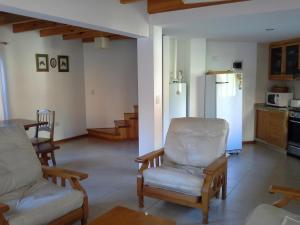 a living room with a couch and chairs and a kitchen at Las Cuatro Estaciones in San Martín de los Andes