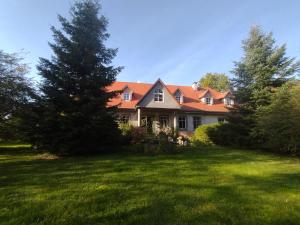 a house with a tree in the yard at Agroturystyka Rawiczówka in Brzeżno