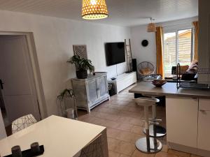 a kitchen and living room with a table and a tv at Villa Mela-Bella in Ouistreham