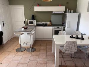 a kitchen with white appliances and a table and chairs at Villa Mela-Bella in Ouistreham