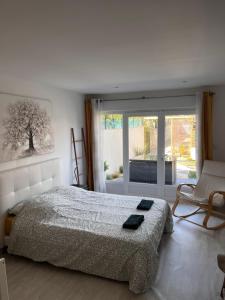 a bedroom with a bed and a chair and a window at Villa Mela-Bella in Ouistreham