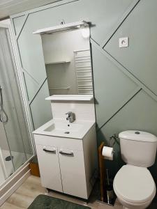 a bathroom with a white toilet and a sink at Villa Mela-Bella in Ouistreham