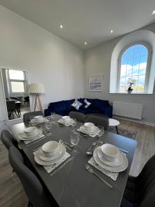 a dining room with a table with plates and wine glasses at Welsh Getaway Apartment - Town Centre in Merthyr Tydfil
