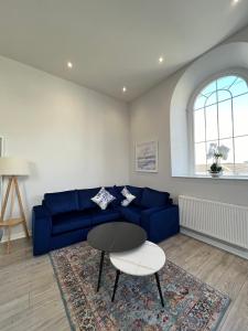 a living room with a blue couch and a table at Welsh Getaway Apartment - Town Centre in Merthyr Tydfil +13 photos