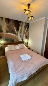 a bedroom with a large bed with a painting on the wall at Nowa Dzielnica Cztery Apartamenty przy Tężni in Busko-Zdrój