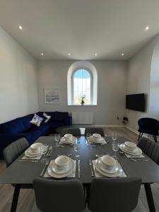 a living room with a table and a blue couch at Welsh Getaway Apartment - Town Centre in Merthyr Tydfil
