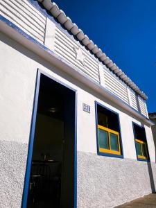オウロ・プレットにあるRecanto do Sol - Lavras Novasの青いドアと黄色い窓のある白い建物