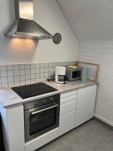 una cocina con estufa y microondas en Jugendstil-Villa am Stadtwald Kühlungsborn, en Kühlungsborn