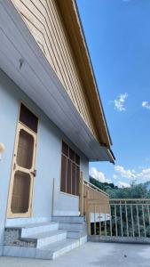 a white house with stairs and a wooden door at Comfort Inn in Chitral